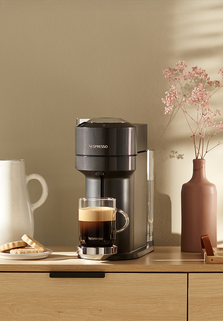 Nespresso machine with coffee mug and cookies on a counter